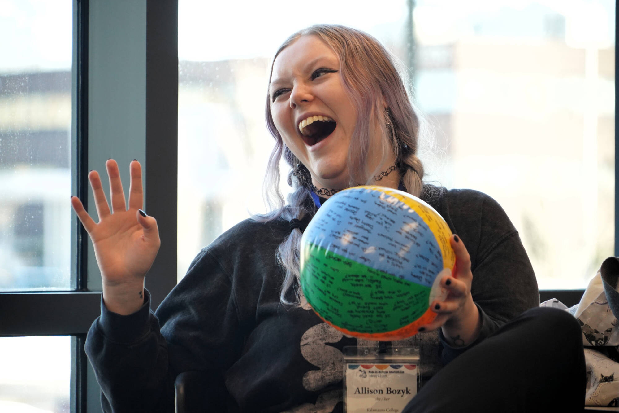 A student laughing while holding a beach ball with writing on it.